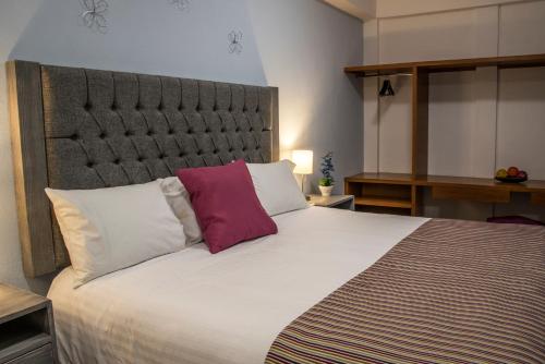 a bedroom with a large white bed with two pillows at Hotel Casa Aurora in Quer&eacute;taro