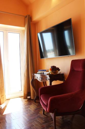 a living room with a red chair and a television on the wall at Quad Avenue in Lisbon