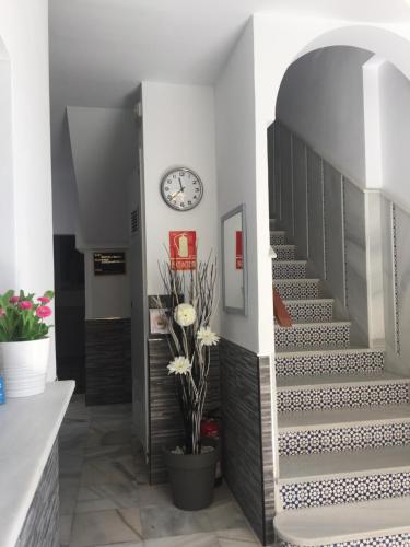 a hallway with a staircase with a clock on the wall at Málaga Centro Hostel in Málaga