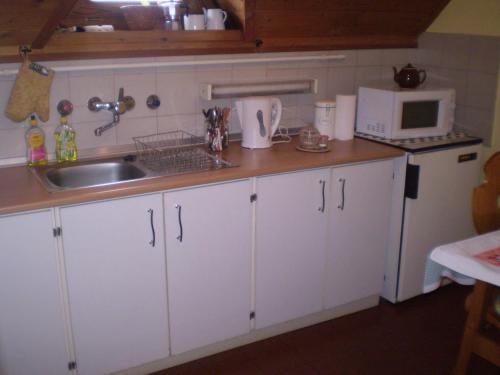 a kitchen with white cabinets and a sink and a microwave at Belvárosi Apartman Kőszeg in Kőszeg