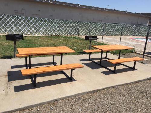 three picnic tables and benches in front of a fence at Mayo Inn in Roswell