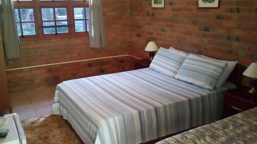 a bedroom with a bed and a brick wall at Pousada Refúgio do Lago in São Francisco de Paula