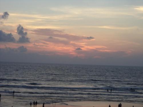 a group of people on the beach at sunset at CALANGUTE BEACH VILLA # 3BHk # POOL # KITCHEN # 300MTS TO BEACH by GR Stays in Calangute