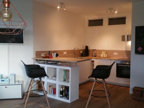 una cocina con 2 taburetes y una barra en Apartment am Zoo, en Krefeld