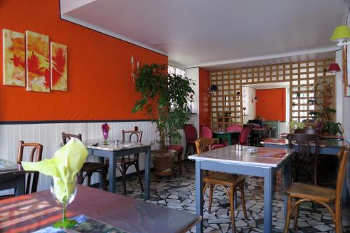 バニェール・ド・ビゴールにあるHôtel du Béarnのテーブルと椅子、オレンジの壁が備わるレストラン