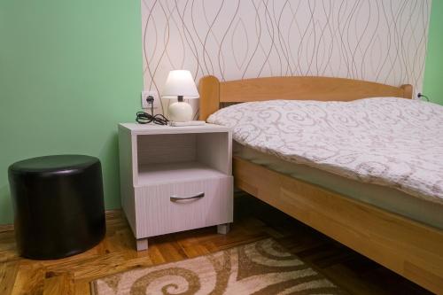 a bedroom with a bed and a nightstand with a lamp at Amfora in Palić