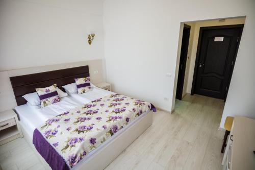 a bedroom with a large bed with purple sheets and pillows at Hotel-Restaurant Ayan Piatra Neamt in Piatra Neamţ