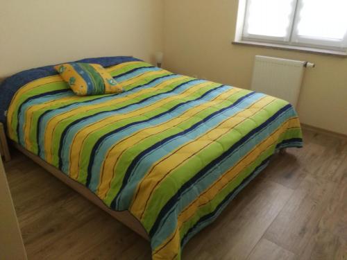 łóżko z kolorową kołdrą w pasku w sypialni w obiekcie Apartamenty Pisz w Piszu