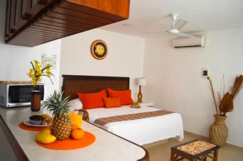 a bedroom with a bed and a table with fruit on it at Arrecifes Suites in Puerto Morelos