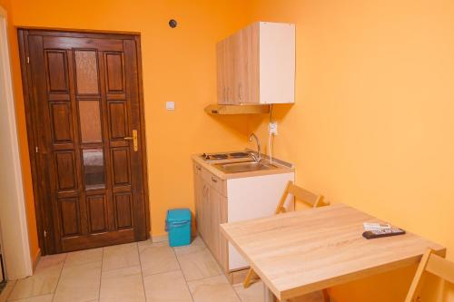 a kitchen with a table and a sink and a door at Amfora in Palić