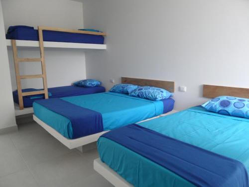 1 dormitorio con 2 camas con sábanas azules y escalera en Condominio Milagros Coveñas en Coveñas