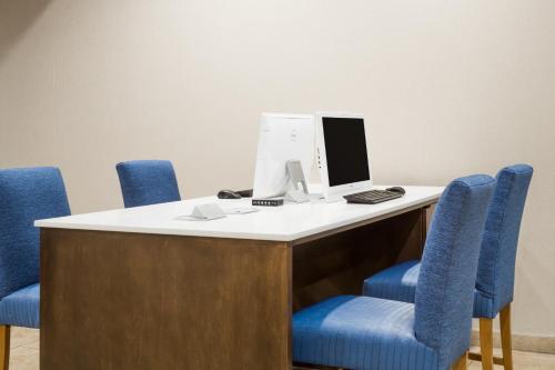 a desk with blue chairs and a computer on it at Wyndham Garden Fresno Yosemite Airport in Fresno