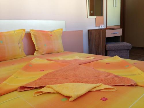 ein Bett mit einer orangefarbenen Decke darüber in der Unterkunft Guest House Lori in Tetewen