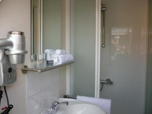 a bathroom with a sink and a shower and a mirror at Hotel Ambrosia in Ypres