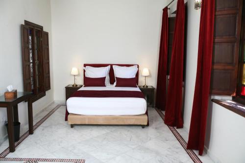 a bedroom with a large bed with red curtains at Riad Batchisarai in Fès