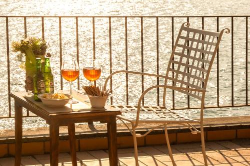 a table with two glasses of wine and a chair on a balcony at The Terrace on the Lake in Marone