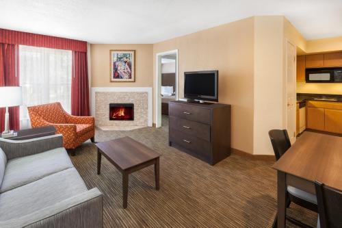 ウォーレンにあるAffordable Suites of America Detroit-Warrenの暖炉付きのリビングルームが備わるホテルルームです。