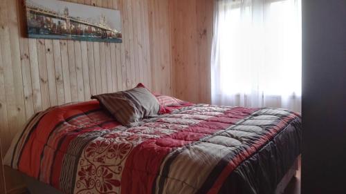 a bedroom with a bed with a red blanket and a window at Vortice Chile Eco-Lodge in Manzanar
