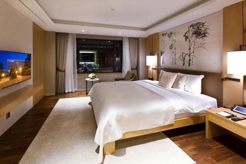 a bedroom with a large white bed and a desk at Hotel Hyundai by Lahan Ulsan in Ulsan