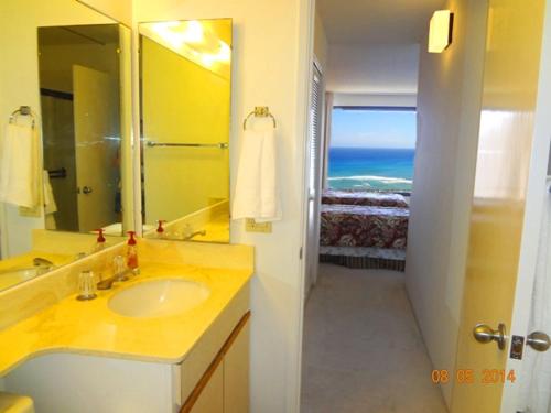 ein Bad mit einem Waschbecken und einem Spiegel sowie ein Schlafzimmer in der Unterkunft Waikiki Vacation 10 in Honolulu