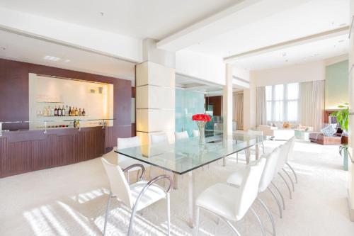 a dining room with a glass table and white chairs at Regal Airport Hotel in Hong Kong