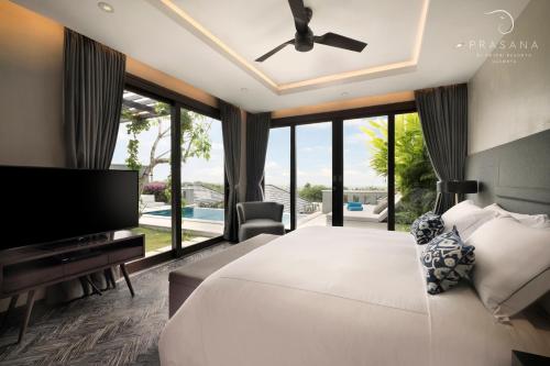 a bedroom with a large white bed and a large window at Prasana by Arjani Resorts in Uluwatu