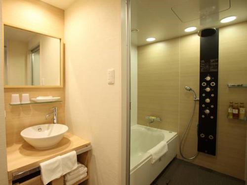 een badkamer met een wastafel, een bad en een douche bij Hotel Keihan Kyobashi Grande in Osaka