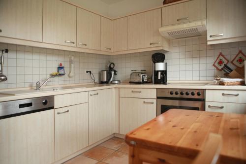 a kitchen with white cabinets and a wooden table at Ferienhaus Marleen in Pritzier