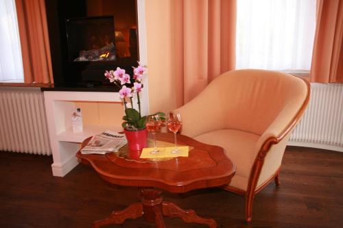 a living room with a chair and a table with flowers at Hotel Modena in Bad Steben