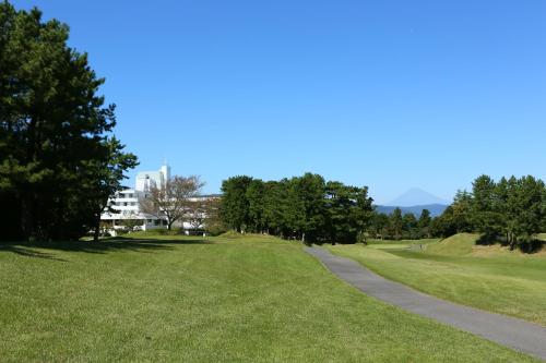 a path in a park with trees and a building at Southern Cross Resort in Ito