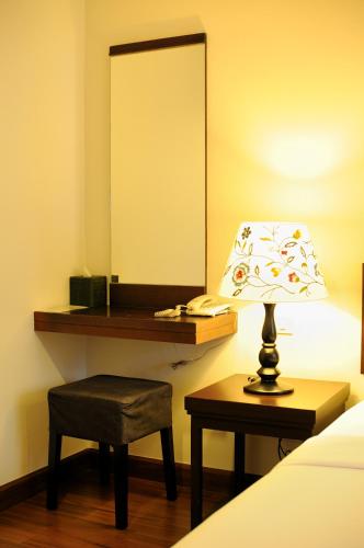 a bedroom with a desk with a lamp and a chair at Kasemsarn Hotel Chanthaburi in Chanthaburi