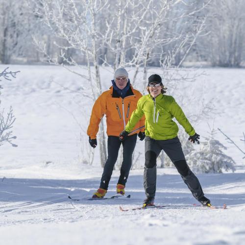 two people are standing on skis in the snow at Hotel Waldfrieden "Das kleine Hotel" in Spiegelau