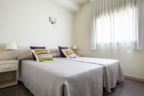 a white bedroom with two beds and a window at Residencia Universitaria Los Abedules in Pamplona