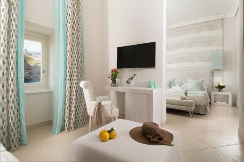 a white living room with a room with a bed and a table at San Michele Suite in Polignano a Mare