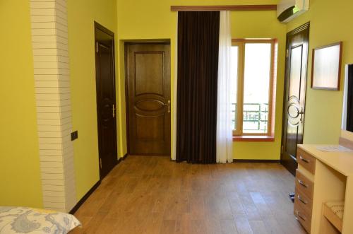 a bedroom with yellow walls and wooden floors and doors at Sheki Panorama Guest House in Sheki