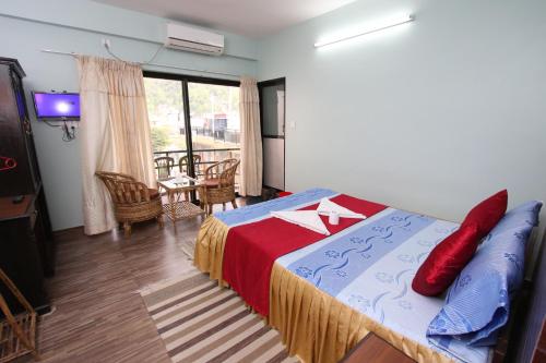 a bedroom with a bed and a living room with a television at The North Face Inn in Pokhara