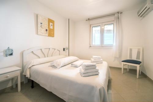Un dormitorio blanco con una cama con toallas. en Apartamentos Marina d'Or Beach 2ª Linea en Oropesa del Mar