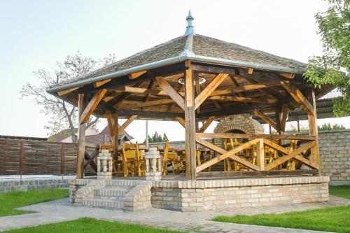 a wooden pavilion with tables and chairs in a yard at Amfora in Palić
