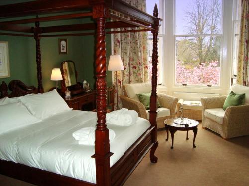 Lochinver Guesthouse في آير: غرفة نوم بسرير مظلة وغرفة معيشة