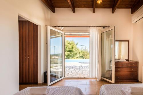a bedroom with a bed and a sliding glass door at Villa Thalea in Tsoukaladhes