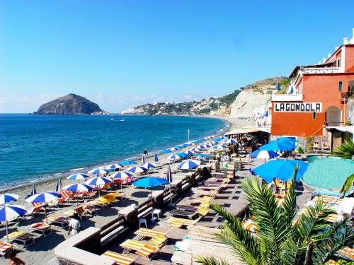 a beach with umbrellas and chairs and the ocean at Hotel La Gondola in Ischia
