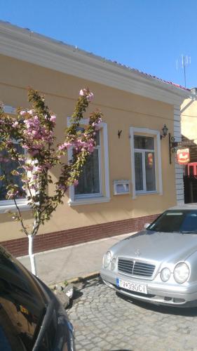 a car parked in front of a white building at Кімнати в центрі in Uzhhorod