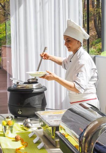 a woman in a chefs hat holding a plate of food at Hotel Cvilín in Krnov