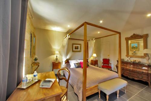 a bedroom with a canopy bed and a wooden table at Les Jardins d'Ungaro / Manoir La Barrière in Le Vigan