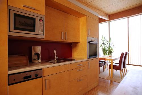 cocina con armarios de madera, mesa y microondas en Ferienwohnung Pichler en Traunstein