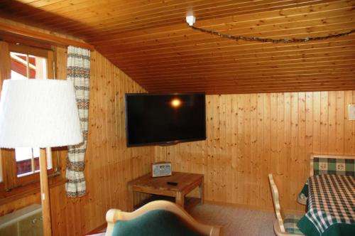 a living room with a tv on a wooden wall at Ferienwohnung Uf dr Liwwi in Grindelwald