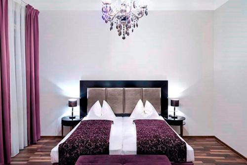 a bedroom with a large bed and a chandelier at Hotel Pension Baron am Schottentor in Vienna