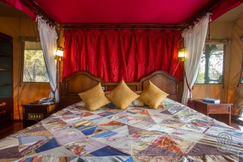 a bedroom with a large bed with a red curtain at Kirawira Serena Camp in Handajega