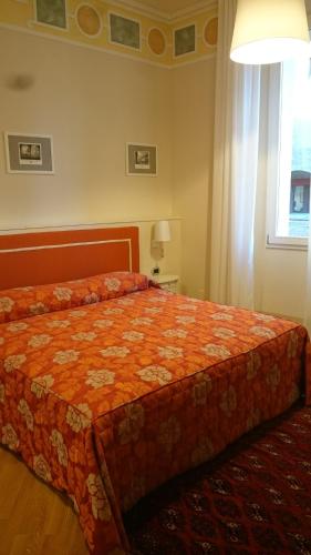 a bedroom with a bed with an orange comforter and a window at Casa Isolani Luxury Rooms Piazza Maggiore 1 in Bologna