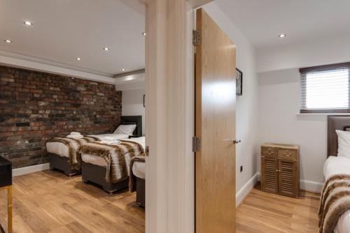 a bedroom with two beds and a brick wall at The Picture House Apartments in Liverpool